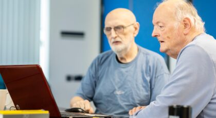 Du senjorai žiūri į kompiuterio ekraną