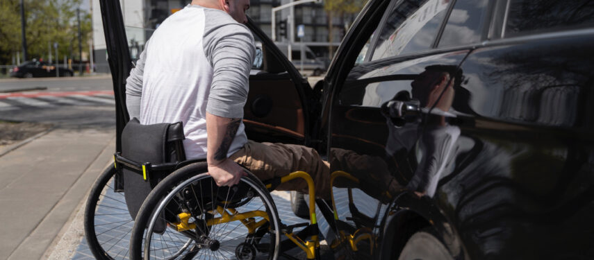 Žmogus su fizine negalia, lipantis į automobilį
