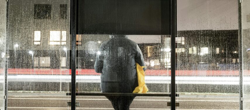 Žmogus sėdi ant suolo autobusų stotelėje