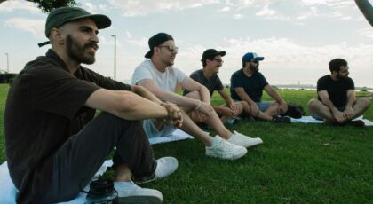 Grupė vyrų sėdi ant žolės