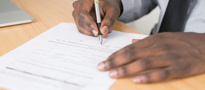 Darbuotojas pasirašo dokumentą, Cytonn Photography nuotr.
