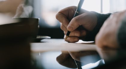 Galima matyti ranką, kurioje laikomas rašiklis, kuriuo pasirašomas dokumentas, pexels.com nuotr.