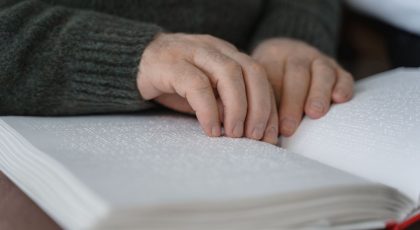 Vyresnio amžiaus žmogaus rankos skaito knyga Brailio raštu, pexels.com nuotr.
