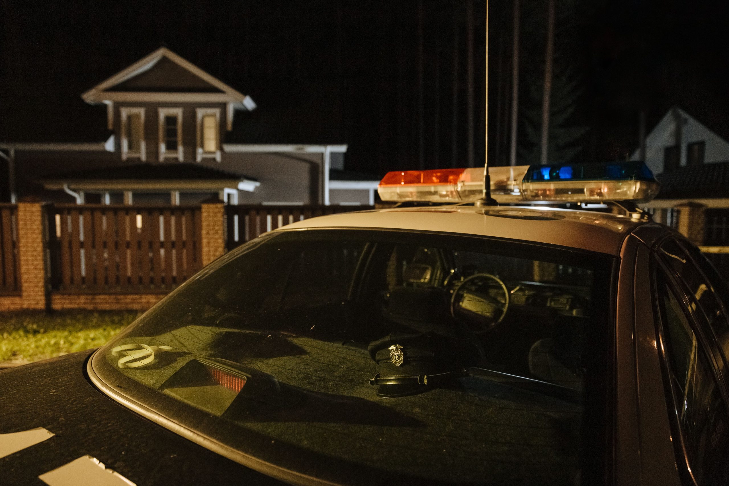 Naktį prie gyvenamojo namo stovi policijos automobilis su švyturėliais, pexels.com nuotr.